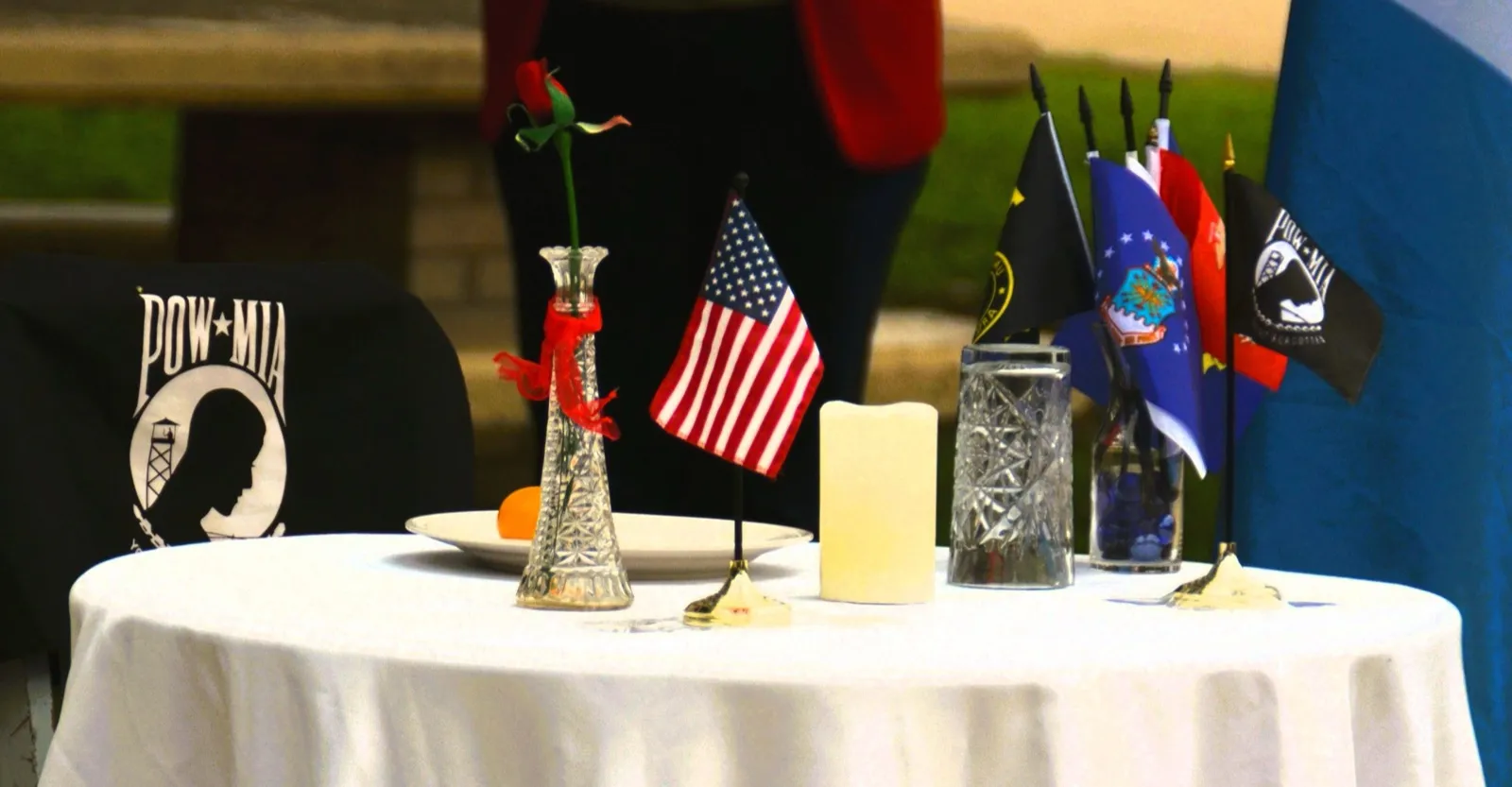 A remembrance table set with a flag, a rose and a candle beside the POW-MIA flag